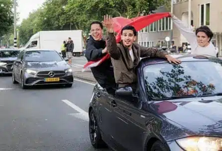 Morocco fans with a flag lean out of car on the streets on Amsterdam to celebrate the World Cup win over the Netherlands.