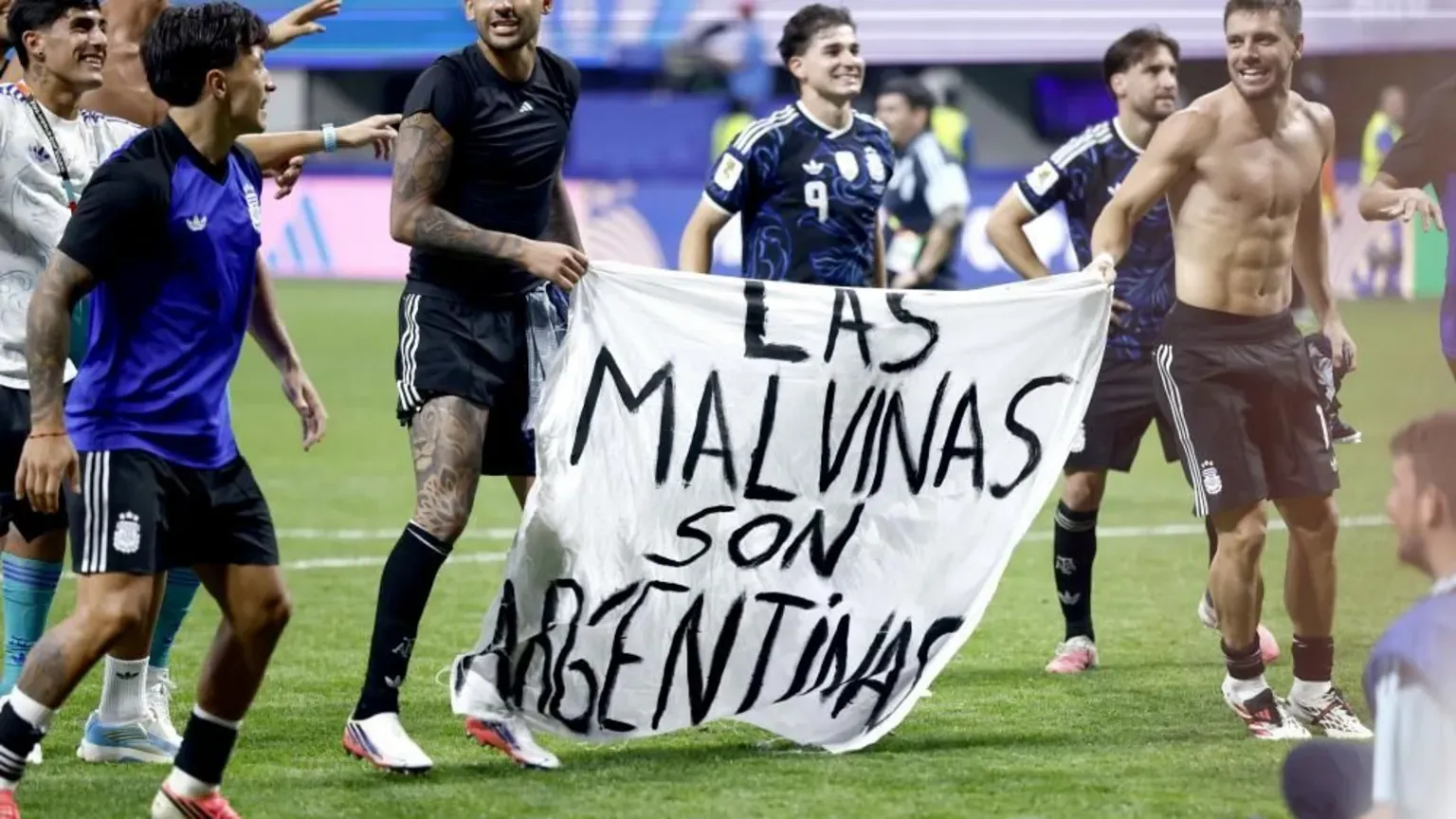 EPA/Shutterstock Argentina players hold a white banner that has "Las Malvinas son Argentinas", which translates as "The Falklands are Argentine", written in black text.