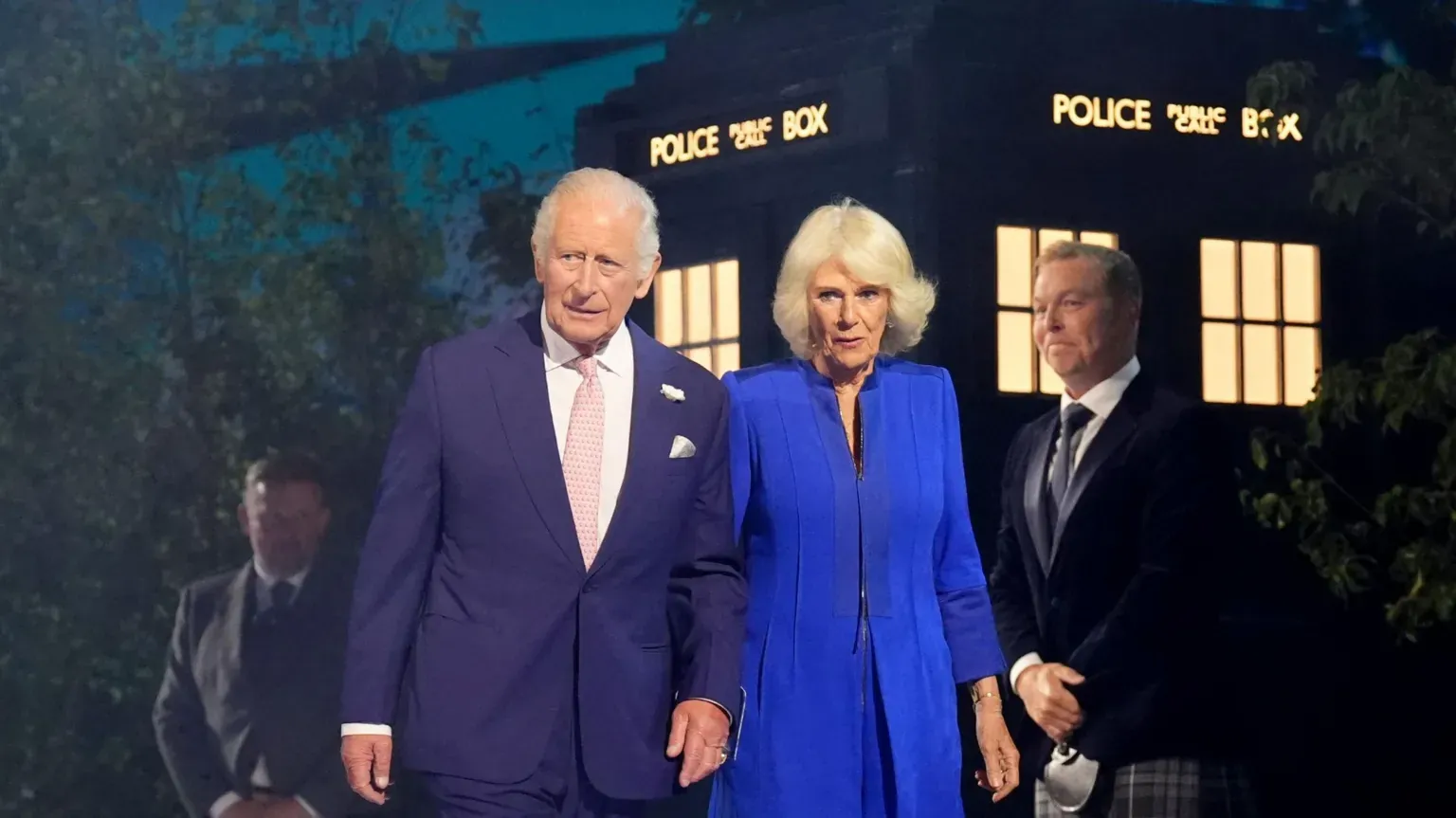 PA Media The King and Queen are walking in front of a Tardis. Sir Chris Hoy is standing behind them.
