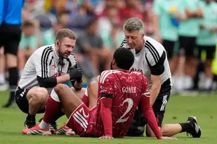 Joe Gomez is helped by trainers after going down early with an injury