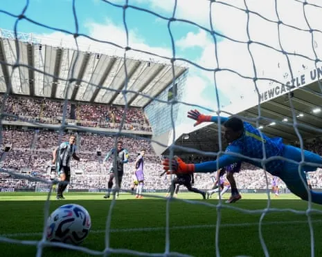 The Bournemouth goalkeeper Djordje Petrovic dives to his left but cannot keep out a shot from Newcastle's Jacob Ramsey.